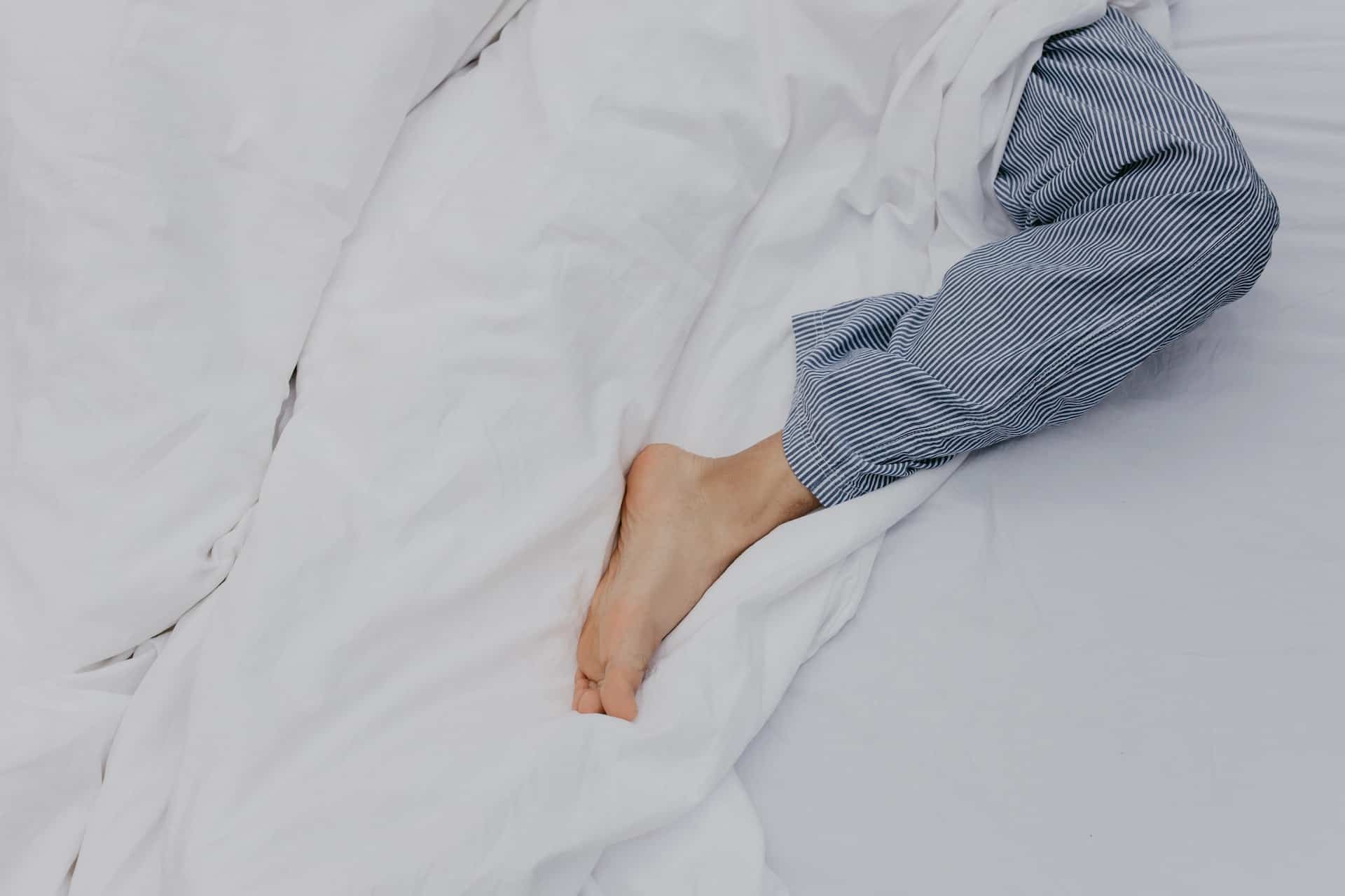 Das Bein einer Person im Bett