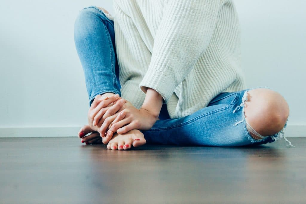 Eine Frau fässt sich an ihren schmerzenden Fuß
