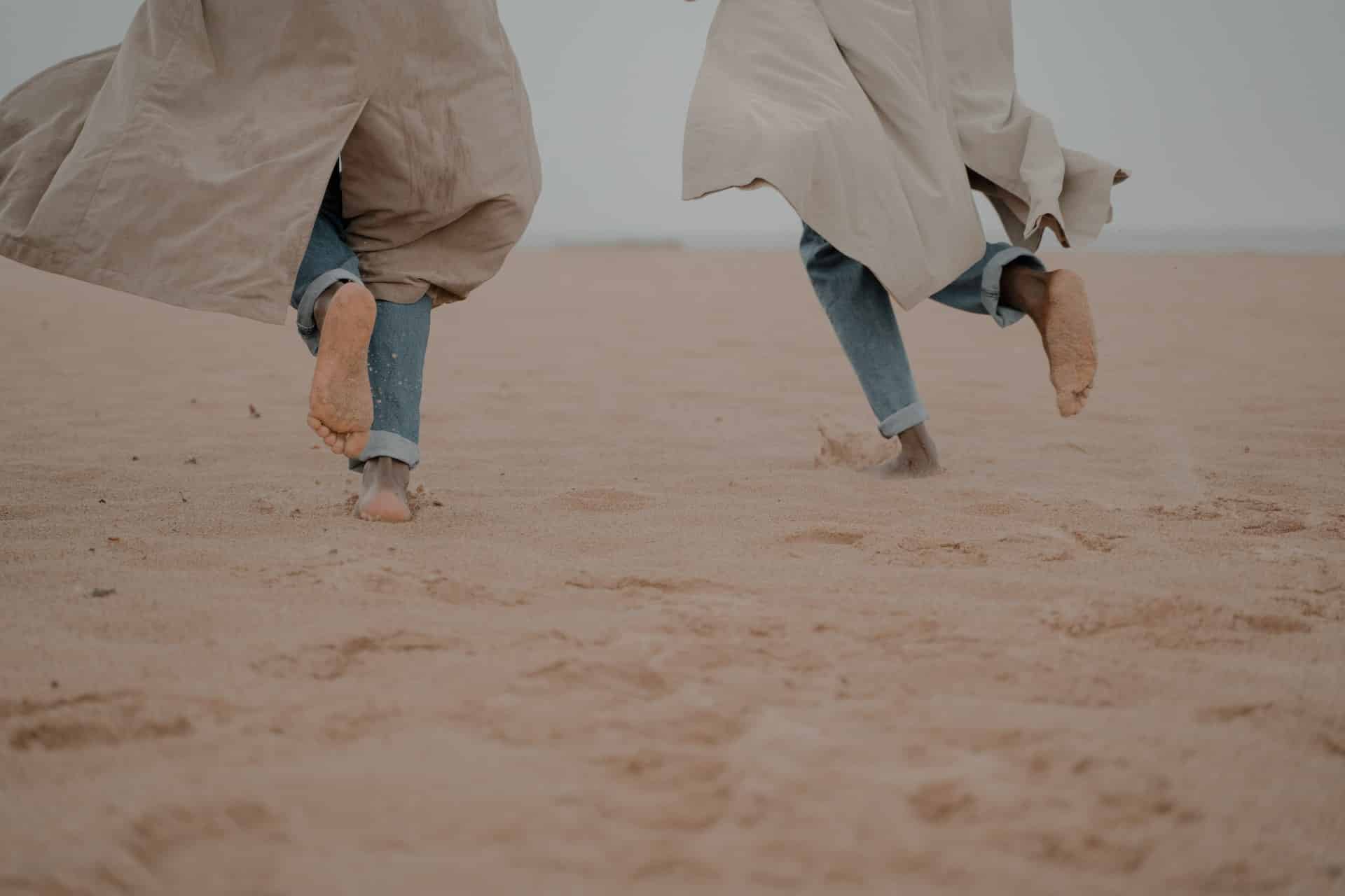 Zwei menschen laufen durch Sand