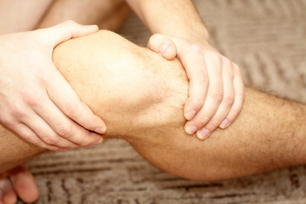 Eine Person greift sich an Ihr von schmerzen geplagtes Knie